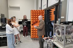 Prof. dr hab. inż. Piotr Jankowski-Mihułowicz wraz z Uczniami w laboratorium RFID. Profesor prezentuje komorę RFID. Inne ujęcie.