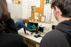 Laboratorium Charakteryzacji Półprzewodników. Prowadzący pokazuje uczestnikom układ na monitorze z użyciem mikroskopu.