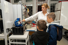 Laboratorium napędów elektrycznych i hybrydowych. Prowadząca tłumaczy zasadę działania silnika.