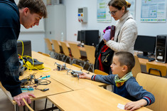 Laboratorium Smart Grid. Student KN pokazuje zwiedzającemu drony. Na zdjęciu zwiedzający, laboratorium oraz obiekty latające.