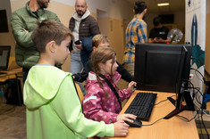 Hol budynku A. Stanowisko KN SKNI KOD. Na zdjęciu komputer. Zwiedzający grają w grę napisaną przez studentów.