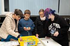 AssecoLab. Uczestnicy budują robota z LEGO Spike. Studentka KN tłumaczy działanie mechanizmów.