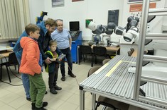 Laboratorium Automatyki, Robotyki i Sterowania. Na zdjęciu uczestnicy pod opieką prowadzącego sterują robotem ramiennym.
